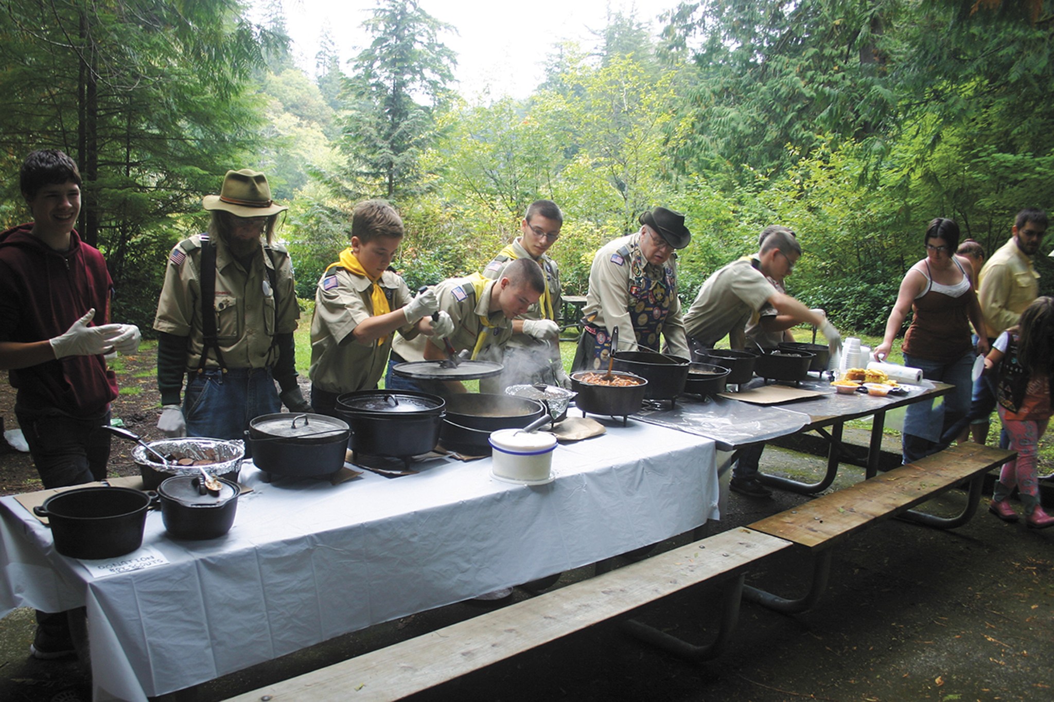 (Corey Morris | The Vidette) Boy Scouts from Troop 4015 of Montesano prepare to feed the masses after a dutch oven demonstration during the 2015 Discover Lake Sylvia Fall Festival at Lake Sylvia State Park. The boy scouts participate in the festival with a demonstration every year. Each scout makes a unique dish. Last year, the dishes dished out of the dutch ovens ranged from brownies to pizza.