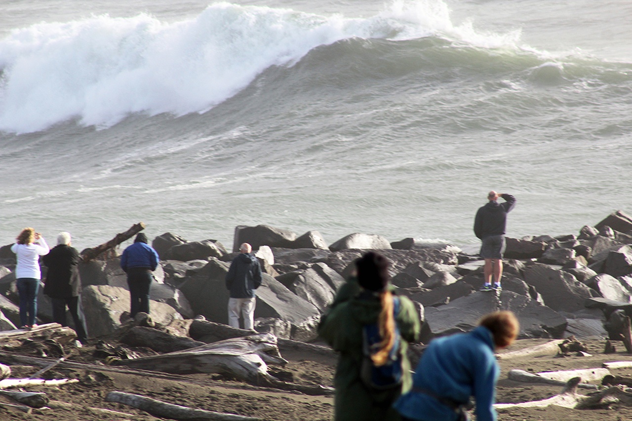 People watch high waves along the North Jetty at Ocean Shores on Friday afternoon. (Angelo Bruscas|The Daily World)