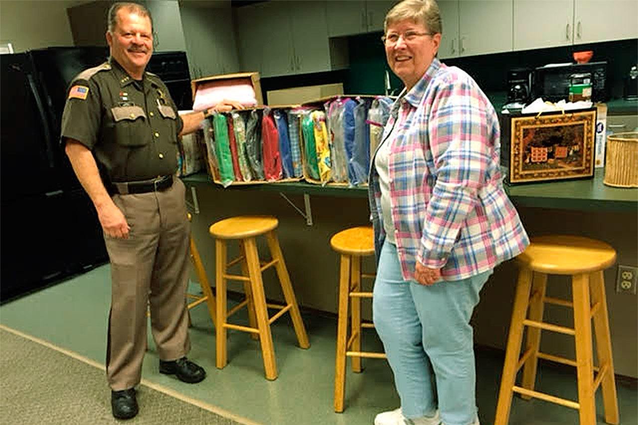 Grays Harbor County Sheriff Rick Scott accepts a donation of 45 children’s quilts from Carolyn Douglas, secretary of the Pieceful Discover’s Quilt Guild. (Photo submitted by Karen Callahan)