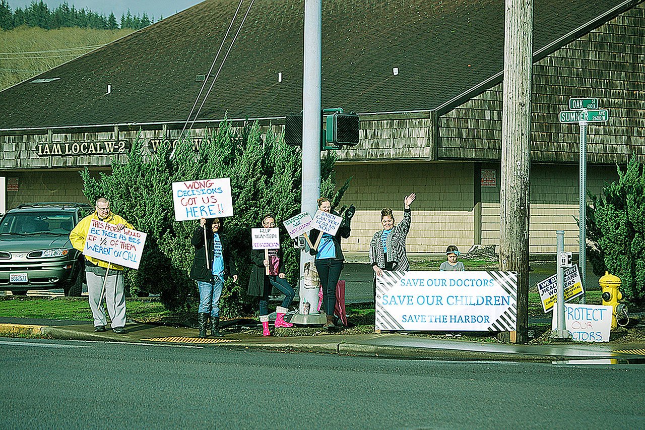 A handful of community members waived signs of support at the intersection of Sumner Avenue and Oak Street Tuesday for outgoing pediatrician Dr. Sean White and Grays Harbor Community Hospital members involved in contract negotiations. (BOB KIRKPATRICK|THE DAILY WORLD)