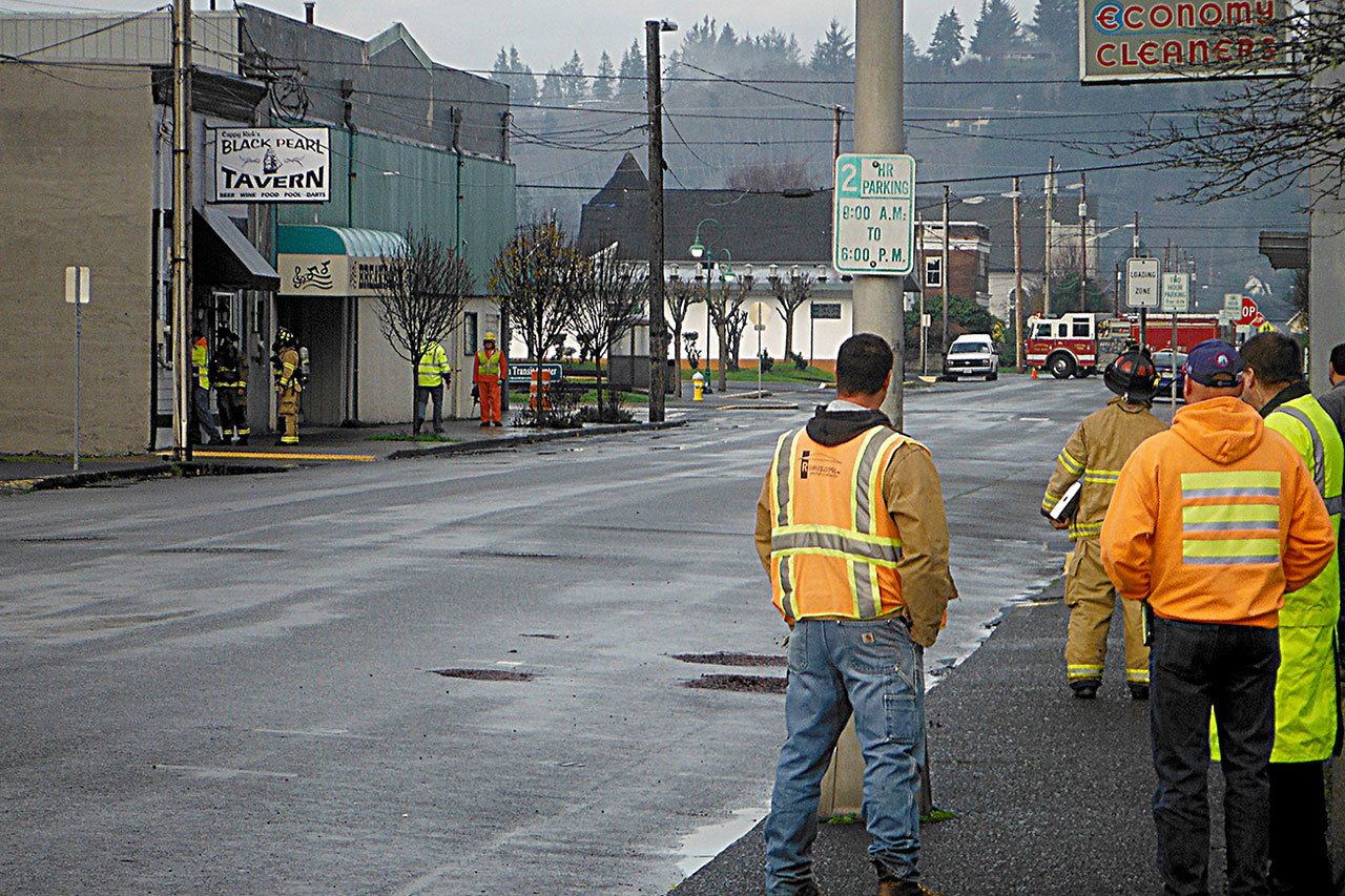 Hoquiam Fire and Cascade Natural Gas personnel investigate the source of the smell of natural gas Thursday morning. This is a view from the command post at Harbor Drug on J and 8th showing responders searching a building on the corner of J and 7th housing the Black Pearl Tavern and Breakroom Lounge. Several blocks of downtown Hoquiam were blocked for about an hour as the investigation progressed, and several businesses were evacuated. The scene was declared clear before 11 a.m., though a source of the odor has not yet been pinpointed. (DAN HAMMOCK|THE DAILY WORLD)