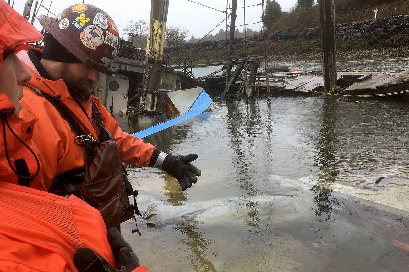 Crews from the Dept. of Ecology assess the source of an oil leak emanating from the former research vessel Hero, which partially sunk on Willapa Bay in the Bay Center area Saturday.