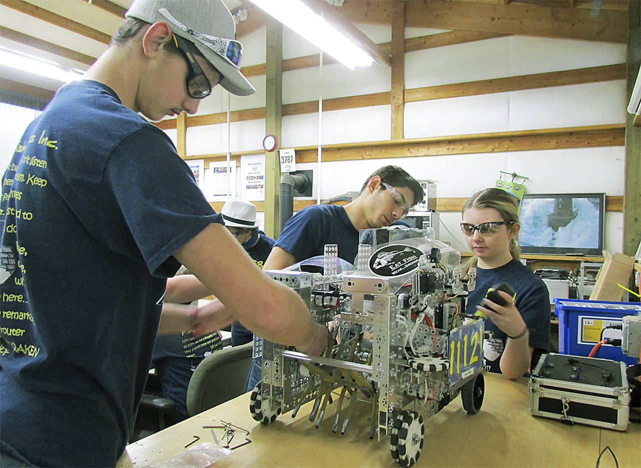 Kaden Smith, Enapa Croy and Kaylie Prieur perform routine maintenance on “The Bullfish,” the Fishy Business team’s robotic competition vehicle. (SCOTT D. JOHNSTON PHOTO)