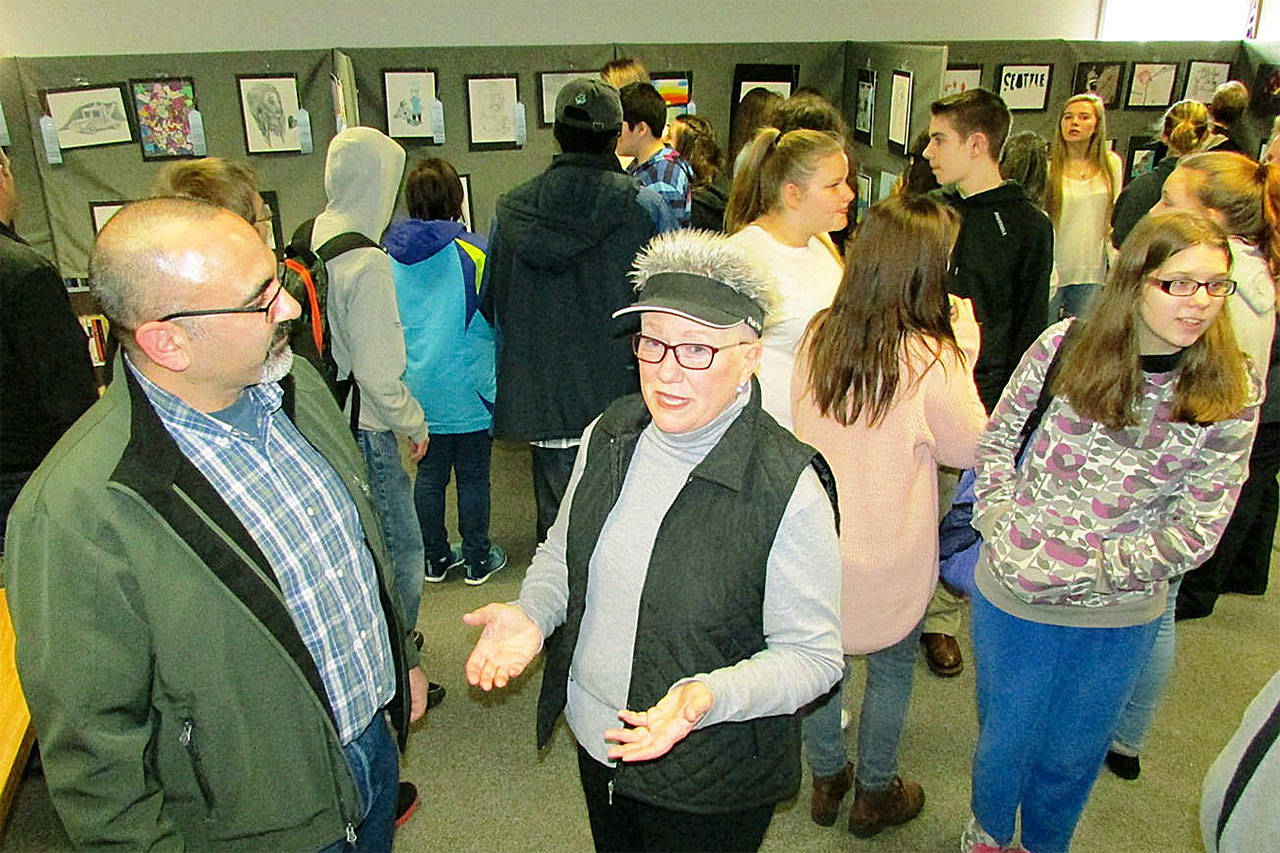North Beach High School art teacher Richard Villar and Associated Arts of Ocean Shores event organizer Kathy Harris enjoying the results of their efforts, and those of 47 young artists at the inaugural Youth Fine Art Open Show artists reception at the Ocean Shores Public Library. (SCOTT D. JOHNSTON PHOTO)