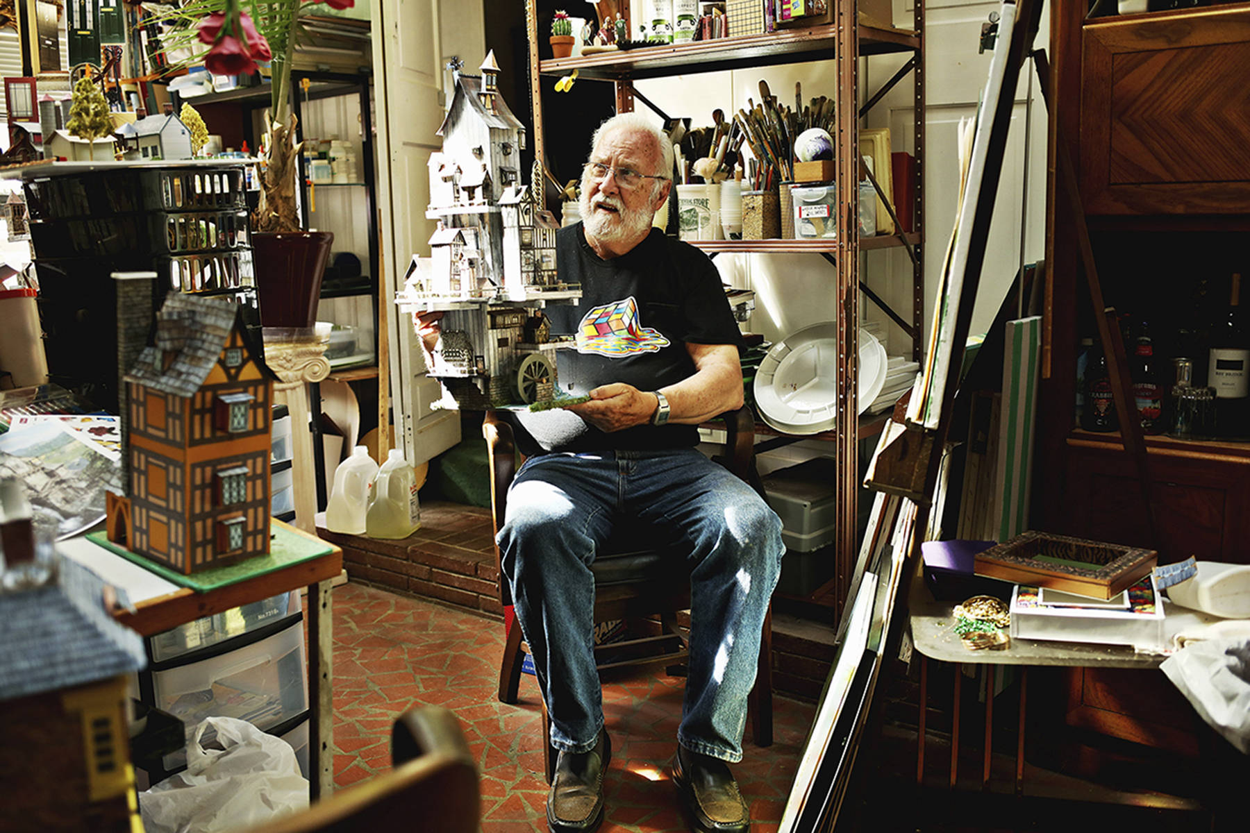 Jim Kellison, 81, sits in his home studio in Raleigh, where he makes his elaborate paper crafts including ornate houses, birds, planes and flowers. (Juli Leonard/Raleigh News & Observer)