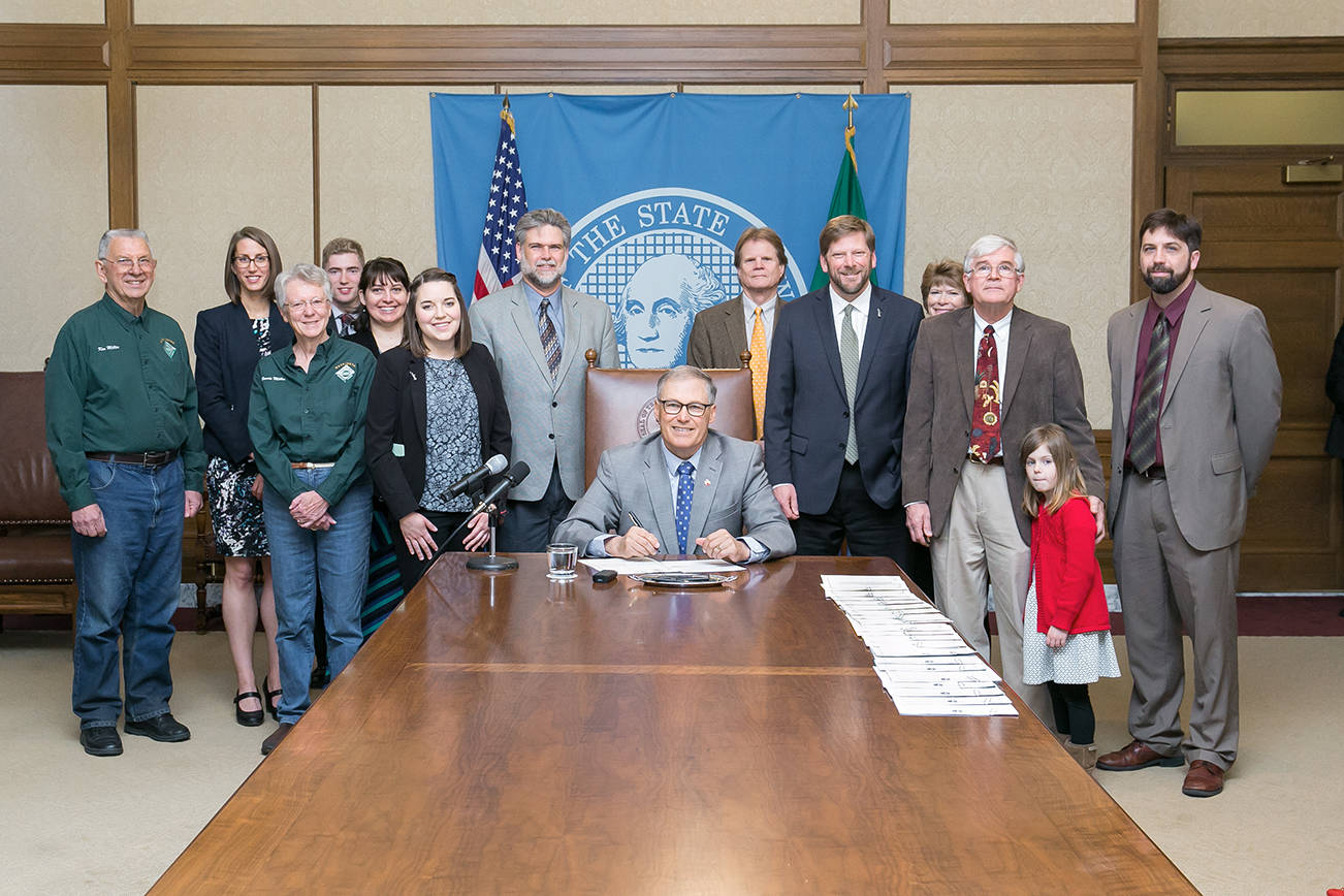 Governor Jay Inslee signs a bill designed to expand the state’s forest riparian easement program. Pictured left to right are Ken Miller, 2013 Tree Farmer of the Year and Director of the Washington Farm Forestry Association; Leah Dobey from the Department of Natural Resources; Bonnie Miller; David Woltjer, Rep. Mike Chapman’s intern; Sarah Temples, Rep. Chapman’s legislative assistant; Rep. Ed Orcutt; Gov. Inslee; Dave Warren with the Department of Natural Resources; Rep. Mike Chapman, bill sponsor; Heather Hansen with the Washington Farm Forestry Association; Sen. Dean Takko; and Jason Callahan with the Washington Forest Protection Association.