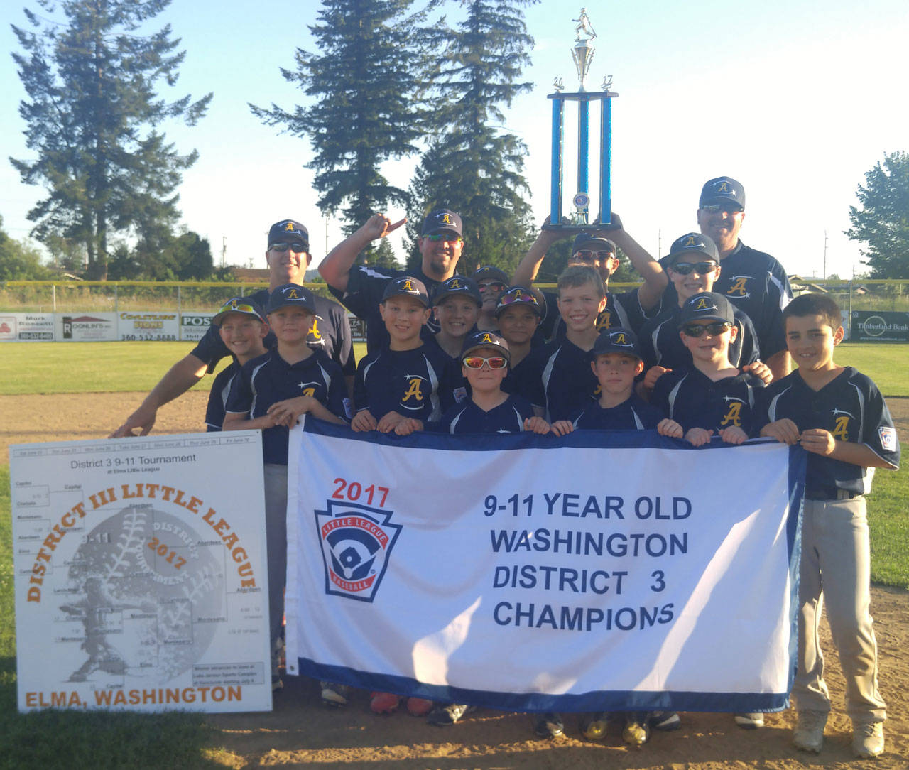 (Rob Burns | The Daily World) Aberdeen Little League’s 9-11 All-Star team holds up the District III 9-11 championship pennant and the championship trophy after defeating Montesano, 11-2, in the district championship game on Thursday at 10th Street Park in Elma.