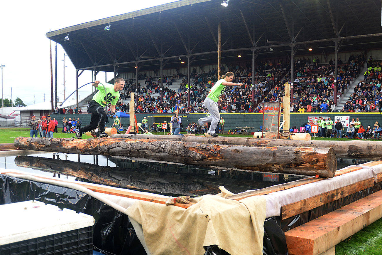 DAN HAMMOCK | THE DAILY WORLD                                Competitors scramble across logs as they compete in the choker-setting event at Loggers Playday Saturday evening. The man on the left who looks like he is losing his balance, in fact, did.