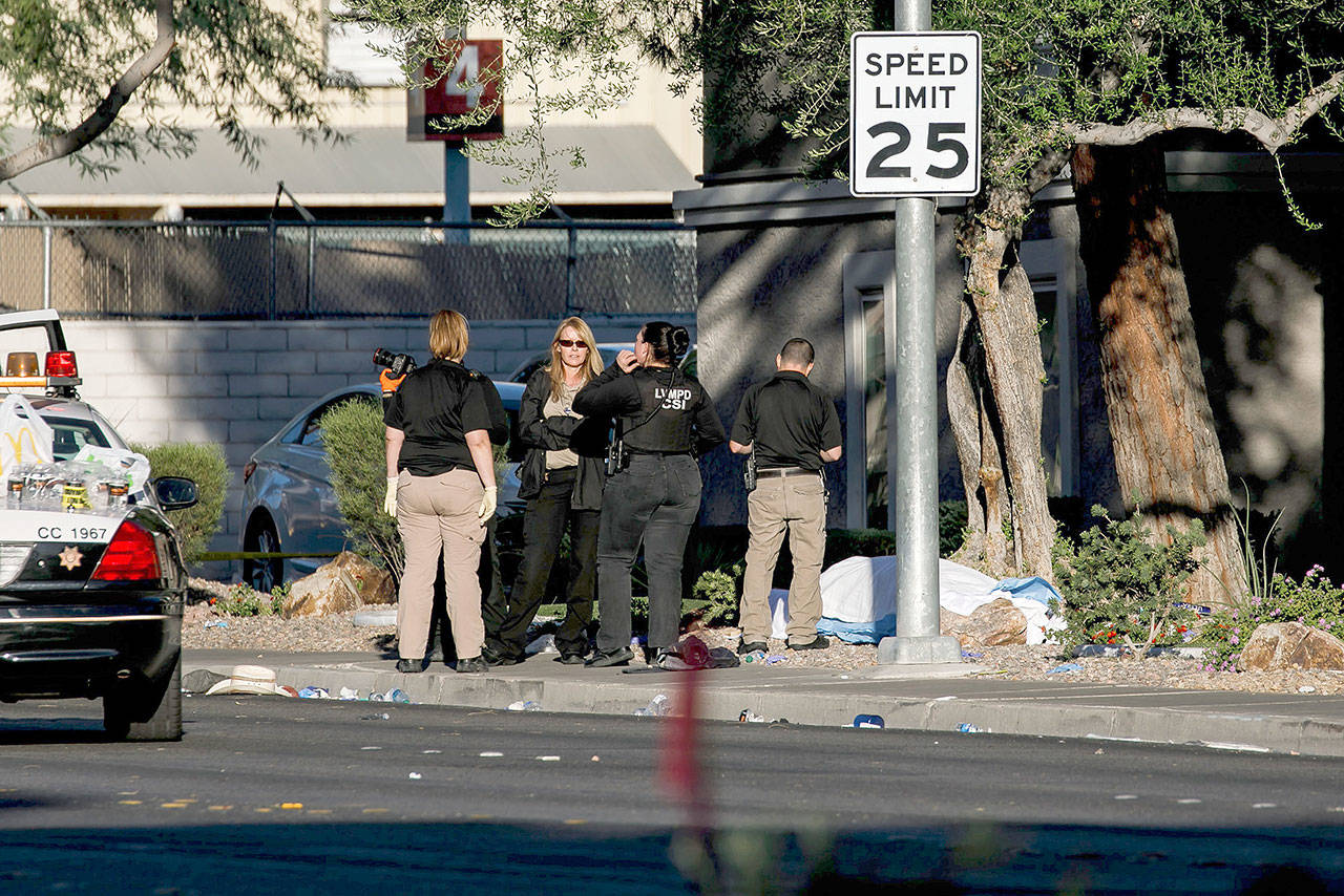 Crime scene investigators stand over a corpse covered with a sheet along Reno Ave, in the aftermath of the mass shooting leaving at least 58 dead and more than 500 injured, in Las Vegason Tuesday. (Marcus Yam/Los Angeles Times)