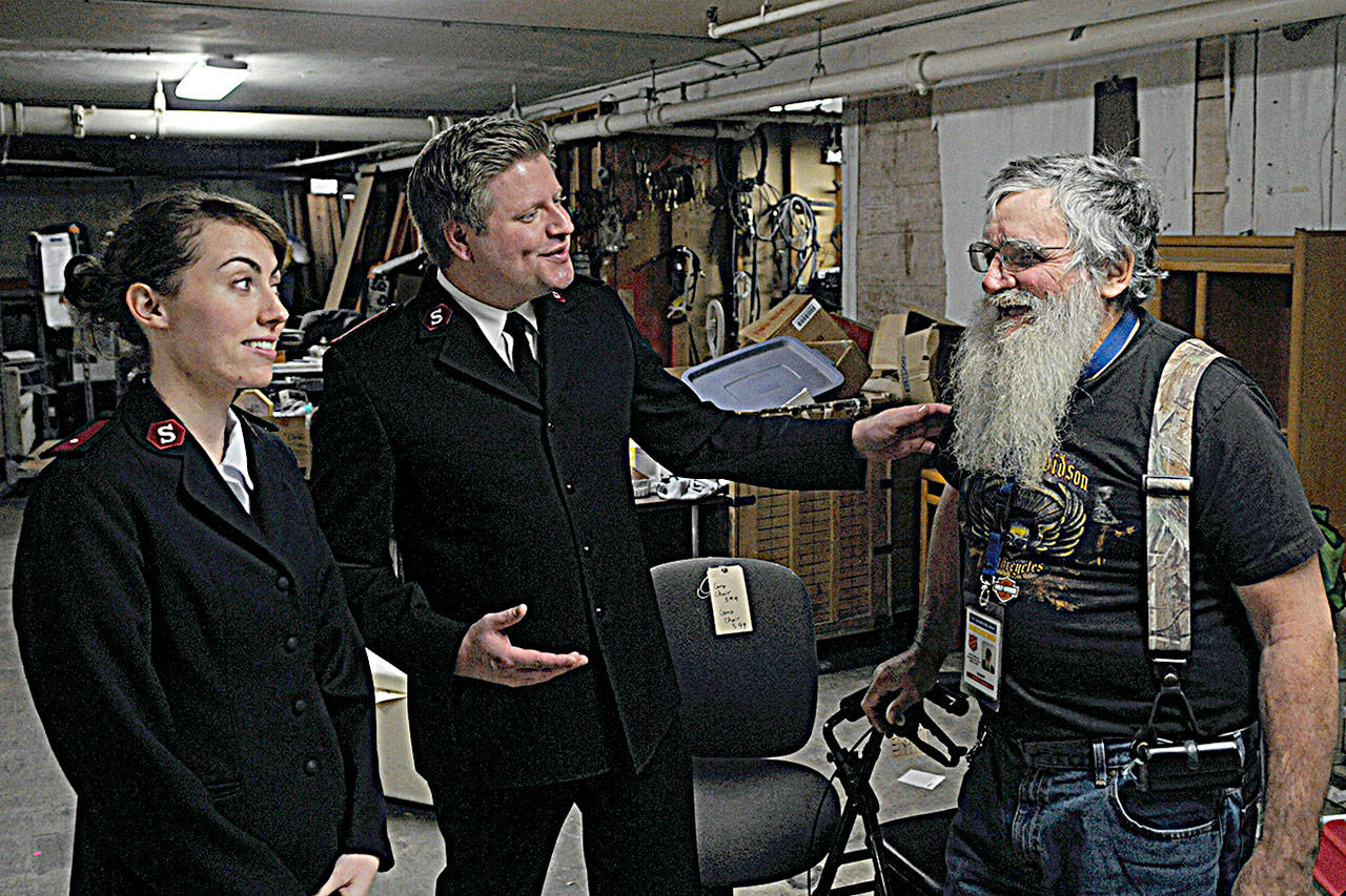 Lt. Claire Hawk-O’Brien and Lt. Lincoln Hawk, center, discuss the store’s inventory with Salvation Army employee Gilbert Newman.