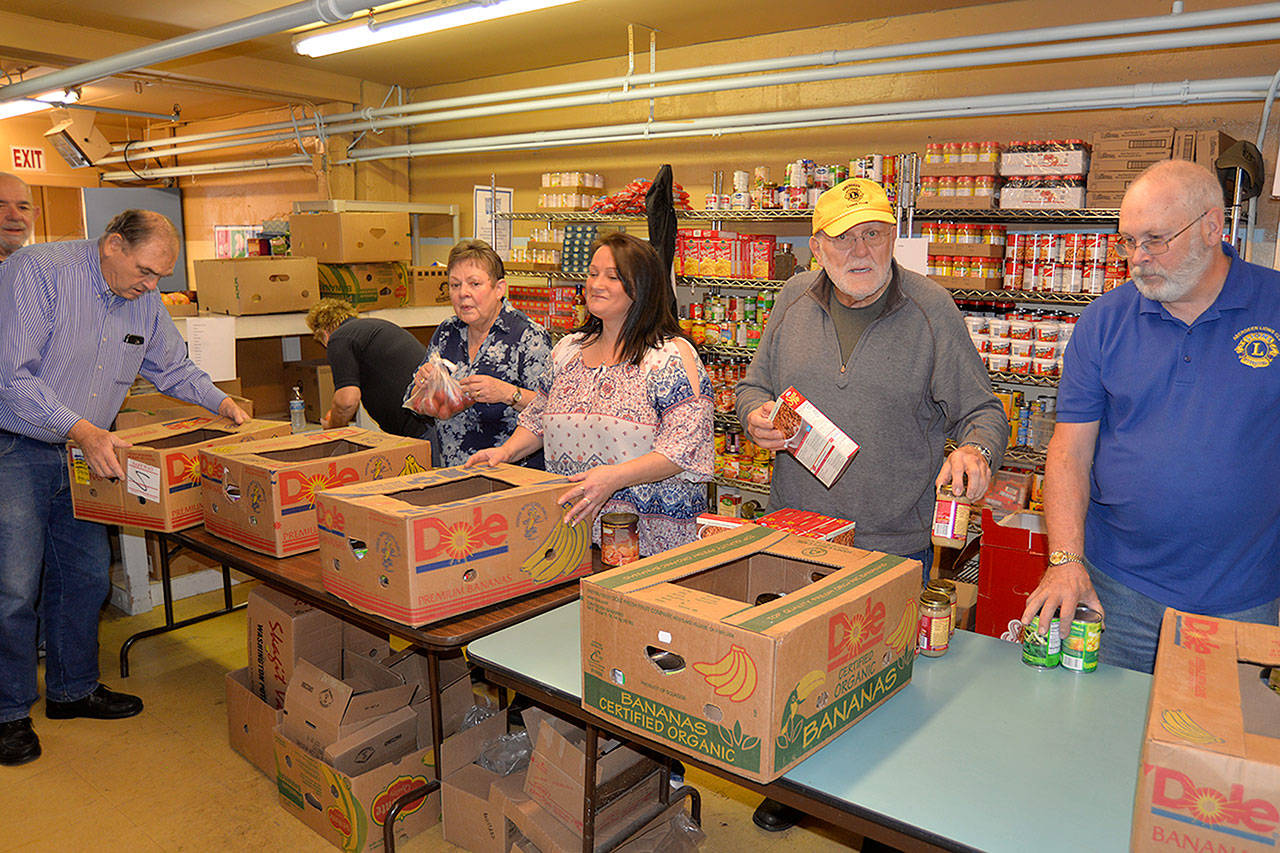 From left, volunteers Al Waters, Phyllis Granahan, Tina Miller from ASAP Business Solutions, Price Chenault and Steve Beck prepare Thanksgiving meals for 131 families at the Salvation Army food bank in Aberdeen. Those who preregistered for meals can pick them up on Monday. (Photo by Louis Krauss)