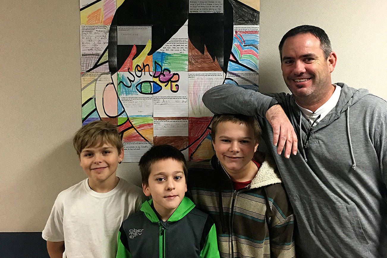 From left, Central Elementary students Eli Lavallee, Blake Anderson, James Young and teacher Chase Taylor stand in front of a student-made collage of what kindness means to them. The school in Hoquiam is participating in a month-long project to encourage students to conduct random acts of Kindness. (Courtesy Denise Pearl)