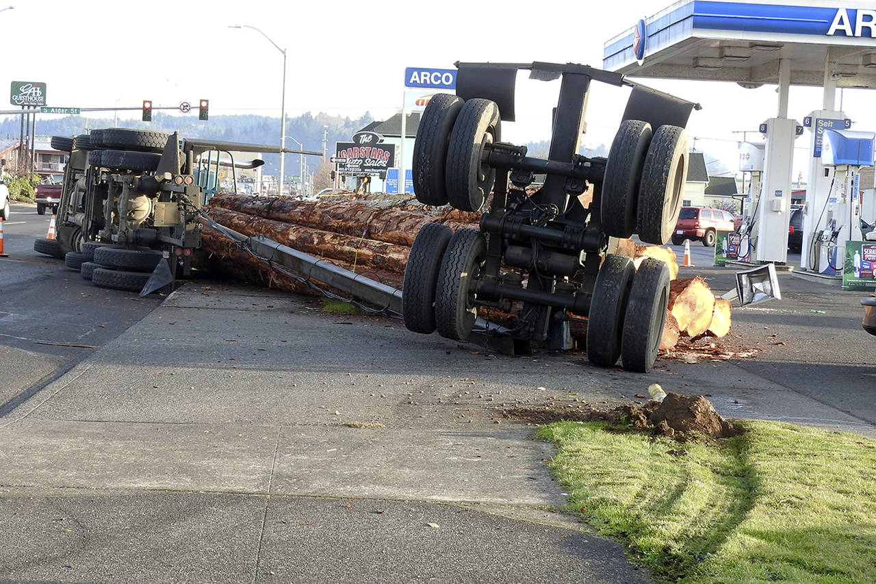 (Kat Bryant | The Daily World)                                This Sweatman’s log truck came apart and dumped its load in front of the Arco at Park and Heron streets.