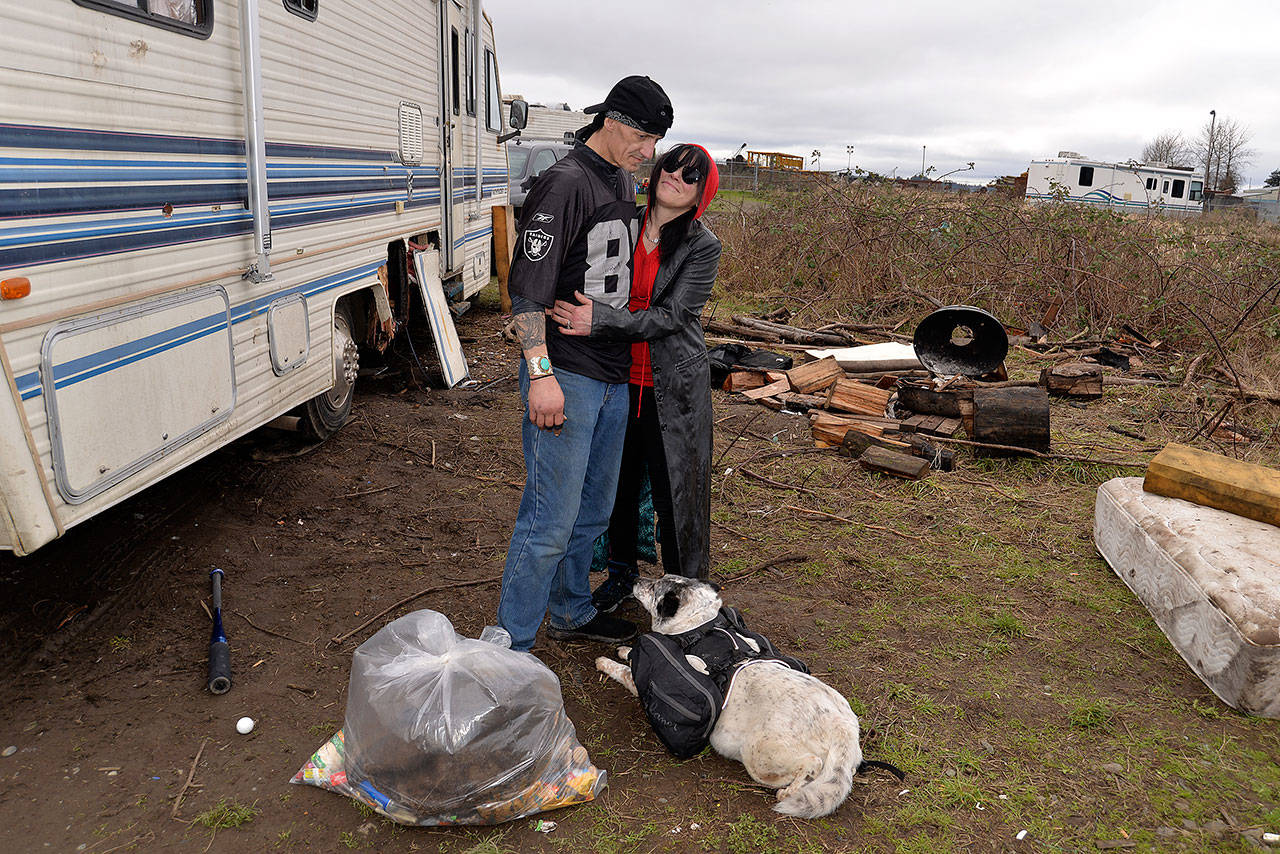 LOUIS KRAUSS | THE DAILY WORLD Brett Hussey and Chloe Morgan stand outside their motorhome along the Chehalis River and a prepared bag of trash. This spot used to have significantly more trash piled up on it, said Hussey, who has lived here a month and a half.