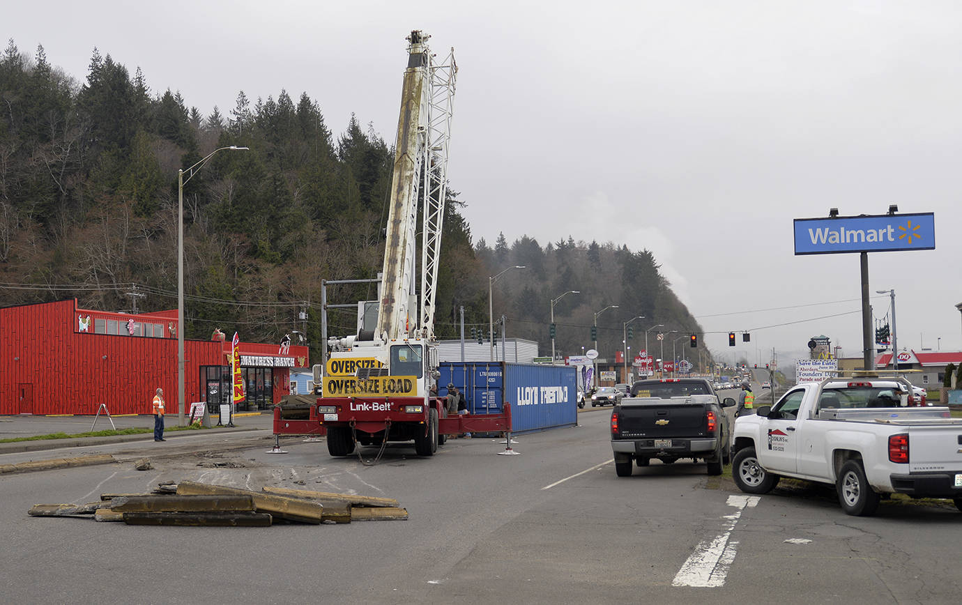 DAN HAMMOCK | THE DAILY WORLD                                A crane from Rognlin’s construction prepares to move a shipping container that tipped over on East Wishkah Street Thursday morning. In the foreground are chunks of what used to be the center concrete barrier between the east and westbound lanes. Traffic westbound was backed up to near Lincoln City during the morning commute.