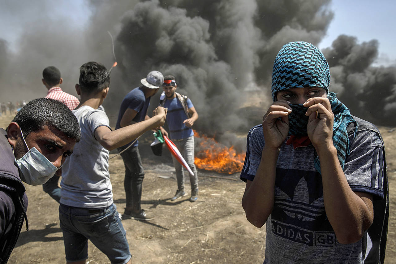 Marcus Yam | Los Angeles Times                                 Protesters fling projectiles at the border fence separating Israel and Gaza in a camp east of Gaza City on Monday.