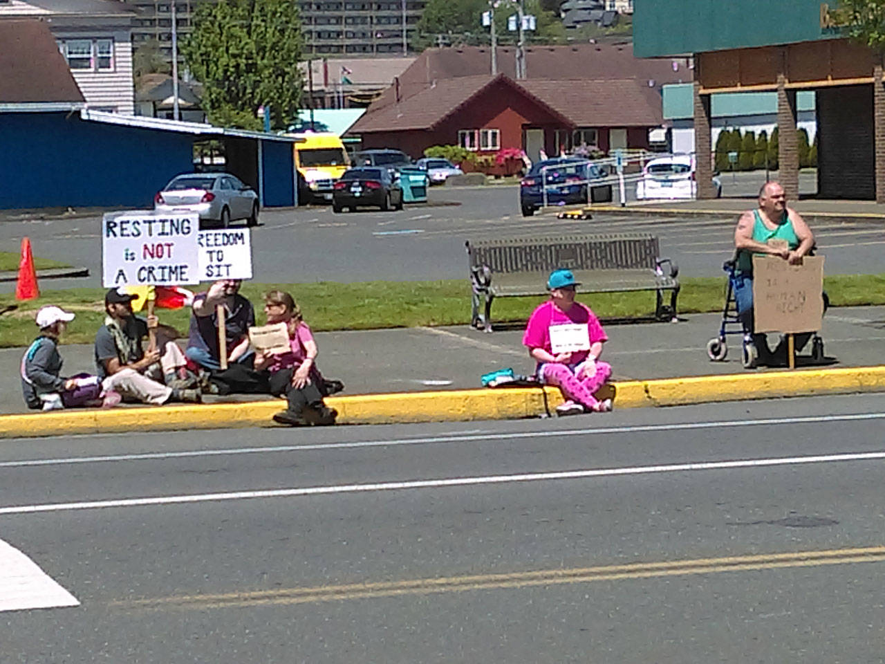 A group of protesters sits at the corner of Market and H streets in downtown Aberdeen expressing their dismay with a decision by the Aberdeen City Council on Wednesday night. (David Haerle | The Daily World)