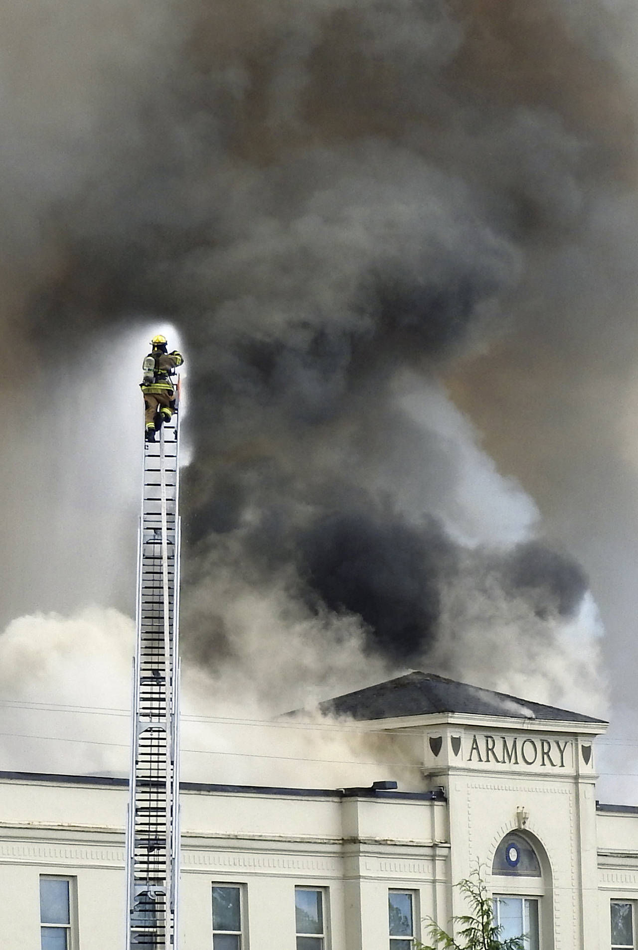 (Kat Bryant | The Daily World) A Westport firefighter sprays water from his ladder truck.