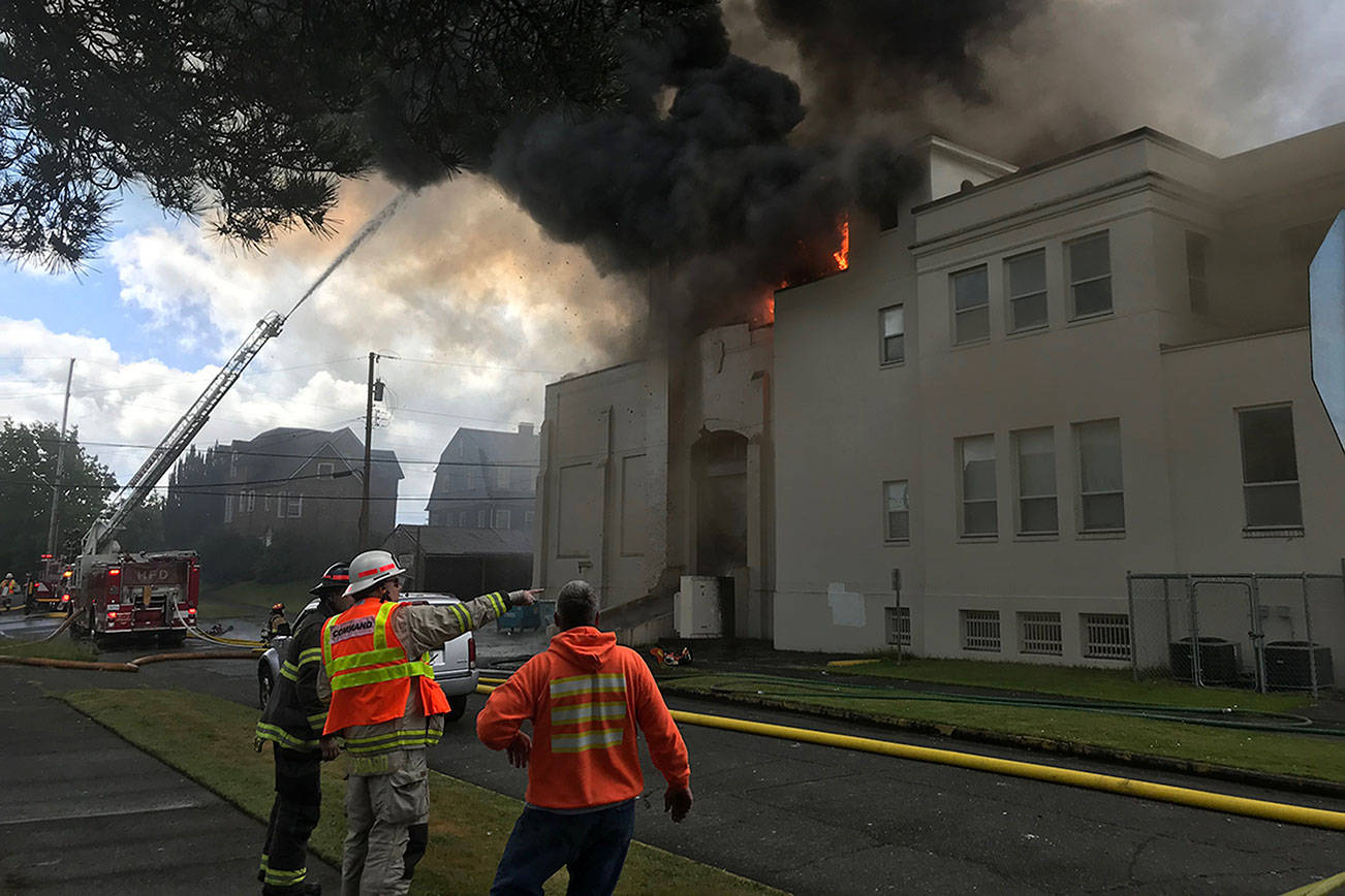 (Louis Krauss | The Daily World) Firefighters discuss their plan at the Armory Building in Aberdeen, which caught on fire early Saturday morning.