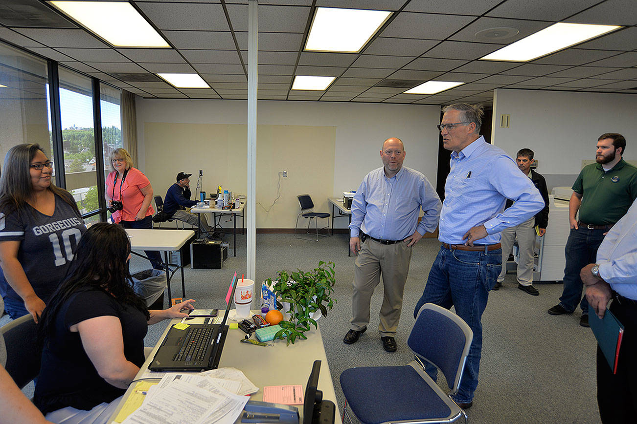LOUIS KRAUSS | THE DAILY WORLD Washington Governor Jay Inslee, blue shirt on the right, speaks with CCAP staff at its new temporary offices in the Seafirst Building in Aberdeen. Aberdeen Mayor Erik Larson, green shirt, and CCAP CEO Craig Dublanko, middle, were also present.