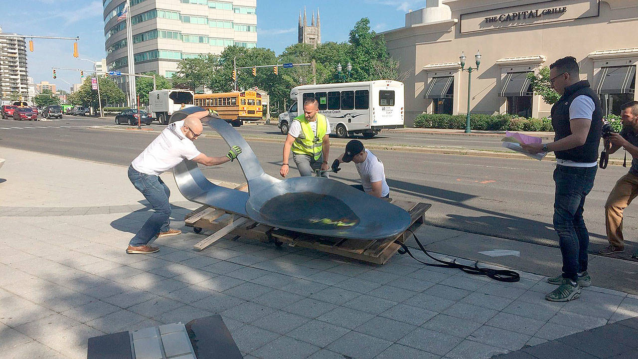 Artist Domenic Esposito, in yellow vest, and Stamford art gallery owner Fernando Luis Alvarez, at right, oversee the installation of an 800-pound, 10 1/2 feet long bent, burnt heroin spoon, in front of the headquarters of Purdue Pharma in Stamford at about 8:30 a.m. Friday, June 22, 2018. The unauthorized installation was a protest against Purdue’s prominent role in the manufacture of opioids. The spoon was removed about two hours later, after Alvarez was arrested on two criminal counts. (Susan Dunne/Hartford Courant)