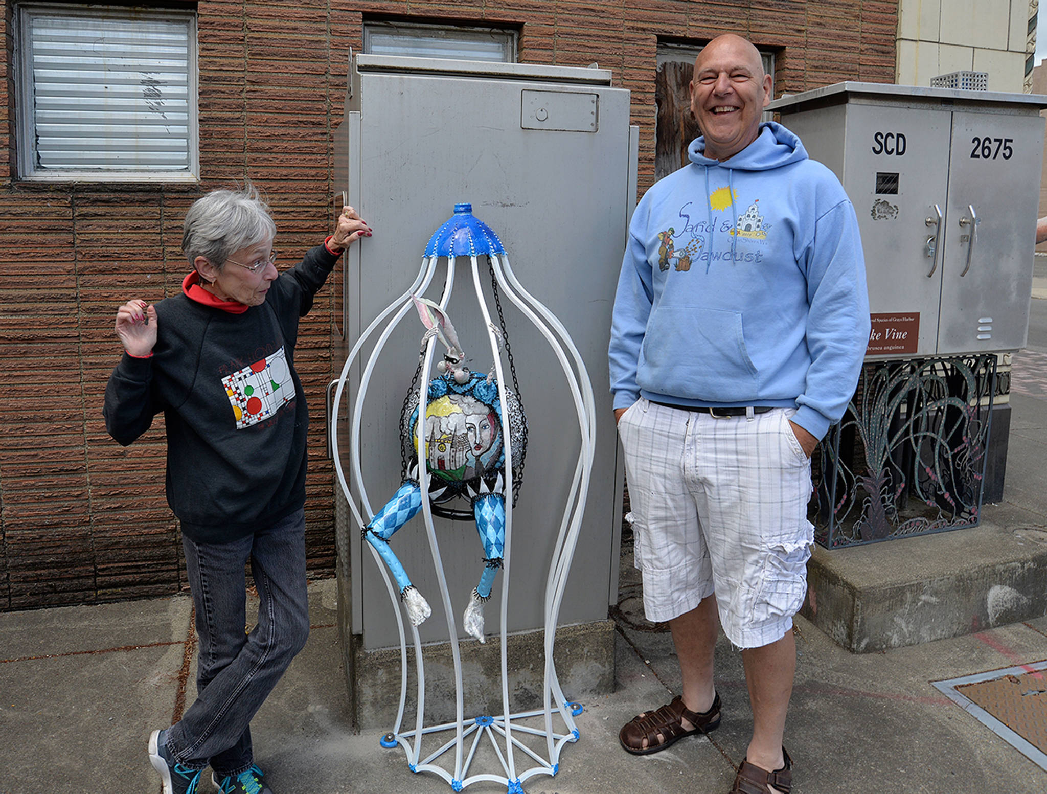 LOUIS KRAUSS | THE DAILY WORLD Sylvia Dickerson, left, and artist Doug Orr stand by the Grizzly Hare statue that was restored and reinstalled this week with three other critters.