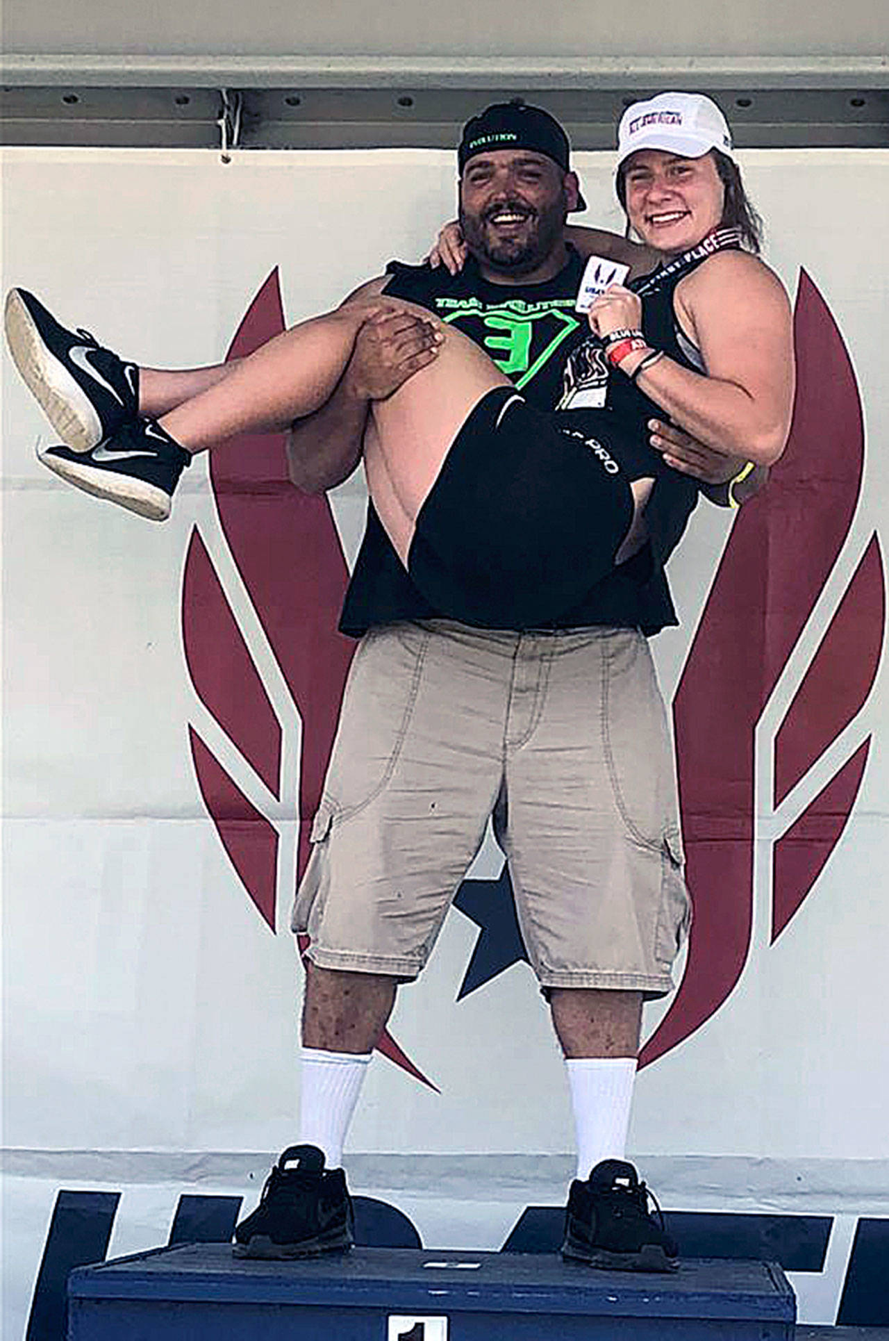 Team Evolution head coach Shaun Straka holds one of his athletes, Karlee Freeman, after Freeman won a Junior Olympic national championship in the discus throw in July. (Photo courtesy of Team Evolution Athletics)