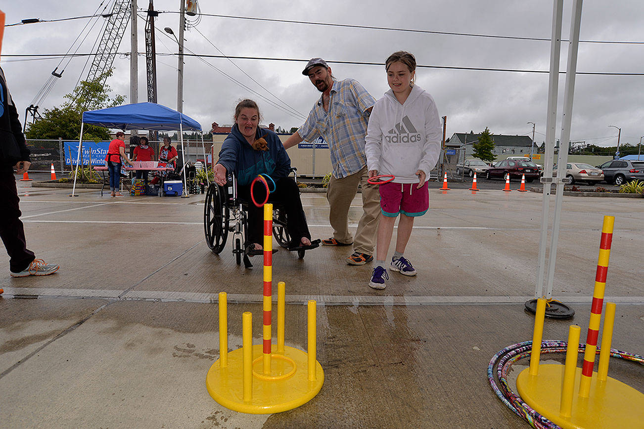 Louis Krauss | The Daily World                                From left, Noelle, Dusty and Heaven Briet attempt the ring toss at Saturday’s Summerfest. Rain forced the event to move to the Tesla charging station lot.
