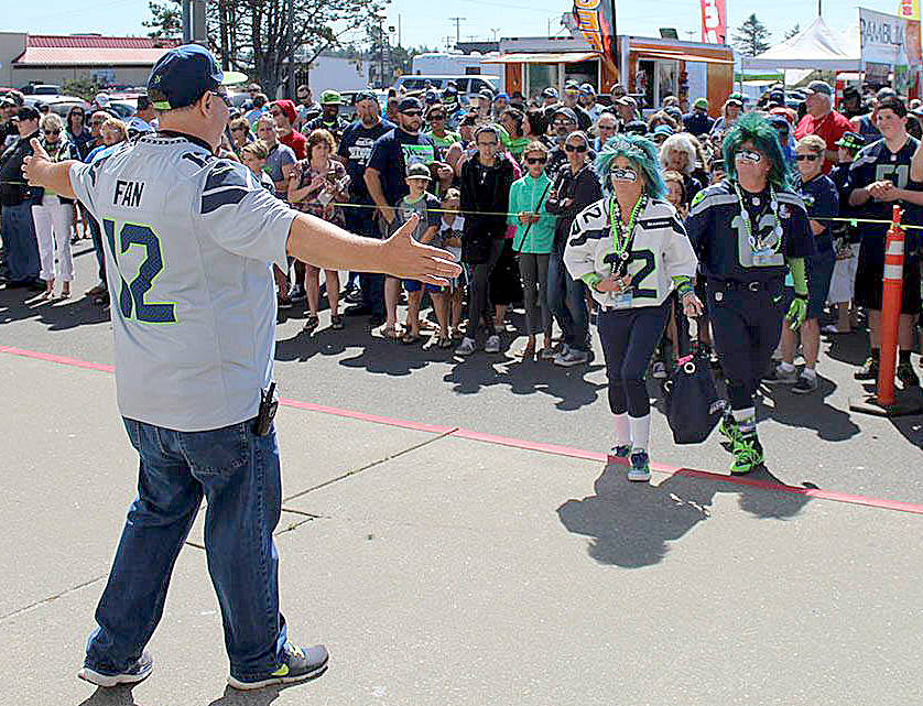 Angelo Bruscas | Twin Harbors Newspaper Group                                Event organizer Terry Johnson, of the Mighty 12s Alliance Seahawks fan organization, greets Mr. and Mrs. Seahawk (Jeff and DeDe Schumaier of Auburn) before the raising of the 12th Man flag at the Ocean Shores Convention Center in 2016.