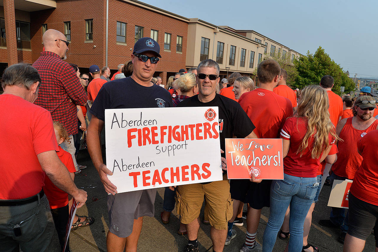 Louis Krauss | The Daily World                                Aberdeen Fire Department members Chris Eisele and Jeremy Laier hold up their signs at Mondays rally to support teachers.