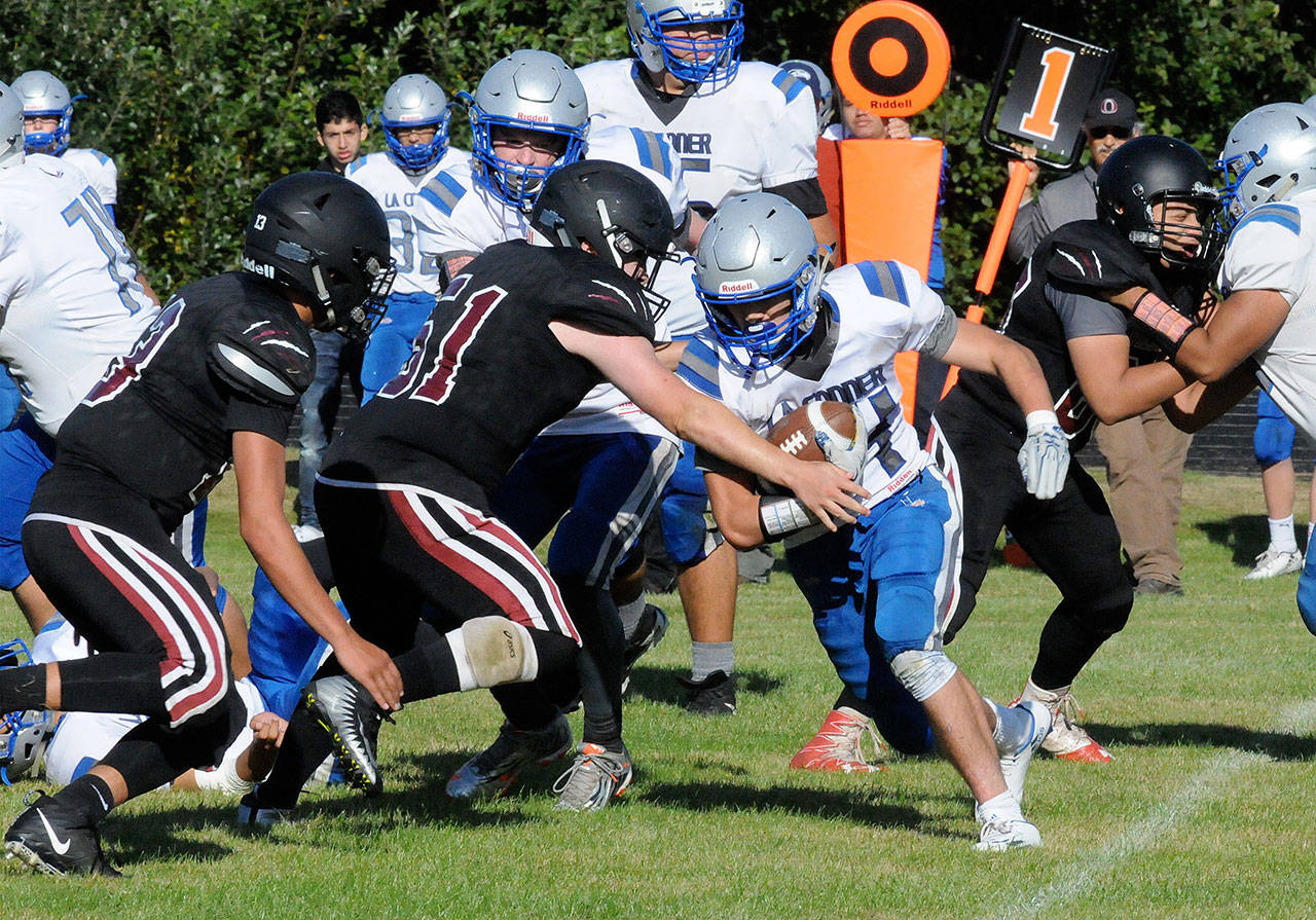 Ocosta’s Gerrick Sweet, middle, tackles La Conner running back Arjuna Adams during the Wildcats’ 14-7 victory on Saturday in Westport. (Ryan Sparks | The Daily World)