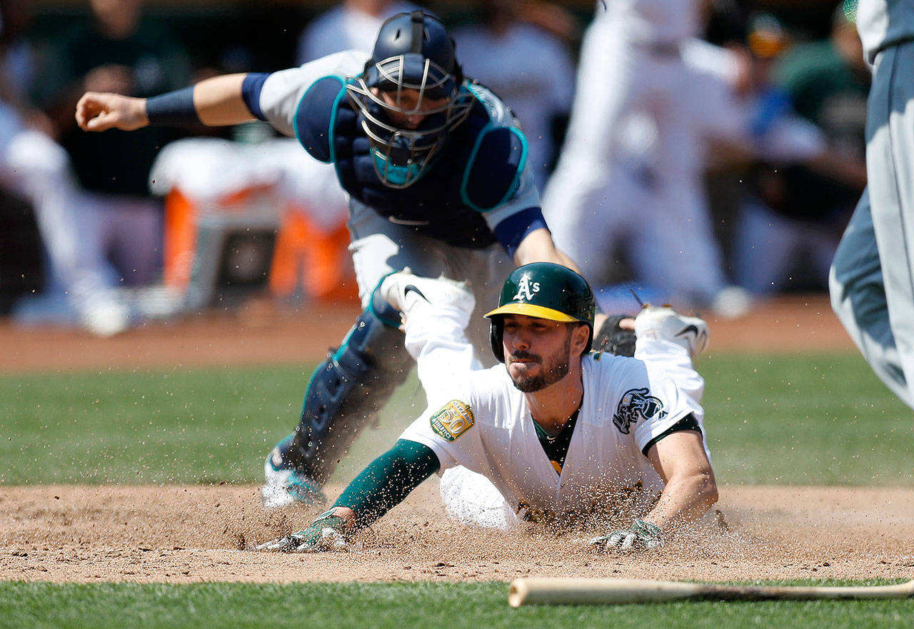 Oakland Athletics’ Matt Joyce (23) slides safely into home plate against Seattle Mariners’ Mike Zunino (3) to score a run on a two-run single hit by Oakland Athletics’ Marcus Semien (10) in the sixth inning on Sunday in Oakland, Calif. (Nhat V. Meyer/Bay Area News Group/TNS)