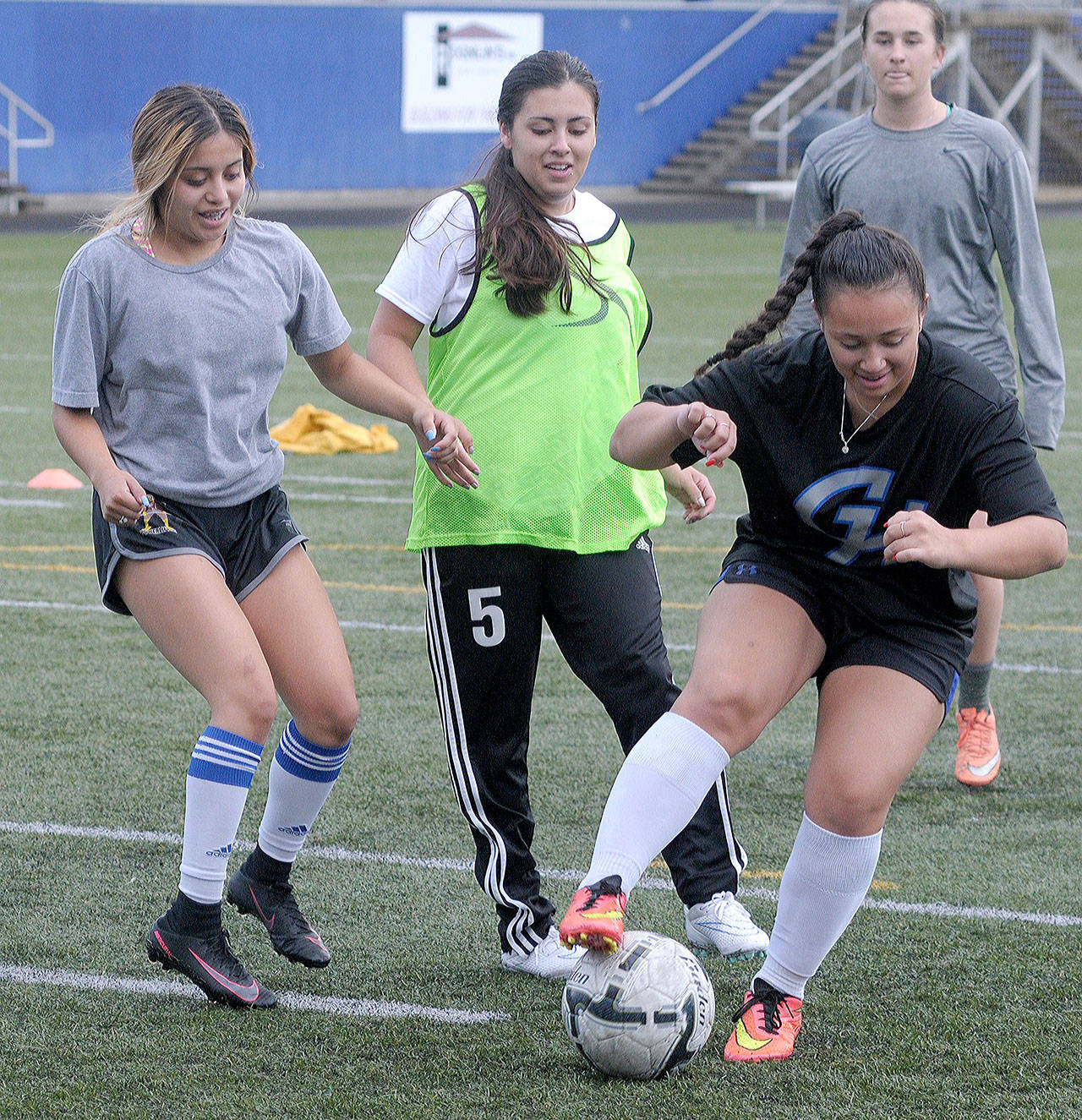 Grays Harbor’s Alicia Cervantes, left, and assistant coach Allie Oropeza, middle, defend against Alex Wilson during a drill at Stewart Filed on Monday. (Hasani Grayson | The Daily World)