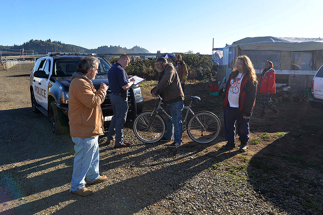Louis Krauss | The Daily World                                A police officer takes notes as he speaks with people living at the major homeless encampment along the Chehalis River in Aberdeen.