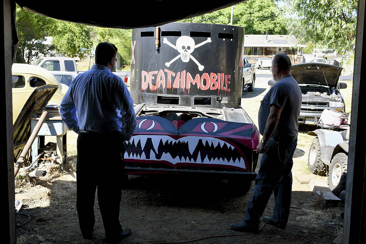 Christopher Reynolds | Los Angeles Times                                 Mechanic Randy Hettwer, right, of Cottage Grove, Oregon, drew the task of repairing the town’s Deathmobile, a replica of the vehicle in the movie “Animal House.” Cottage Grove Chamber President Travis Palmer stands at left.