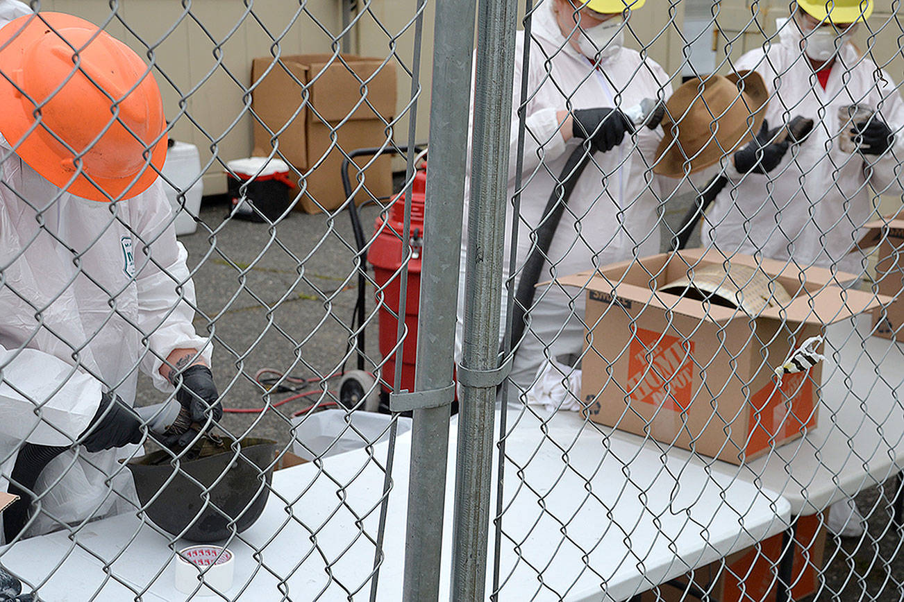 Louis Krauss | Grays Harbor News Group                                Workers from the Restoration Management Company clean helmets and hats recovered from the Armory building in Aberdeen on Wednesday.