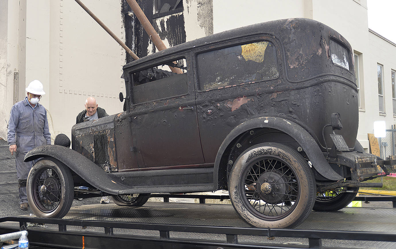 DAN HAMMOCK | GRAYS HARBOR NEWS GROUP                                Ed Lind (in white hard hat) watches as his 1929 Chevrolet is towed from the armory building, where it had been on display at the Aberdeen Museum of History until fire gutted the building June 9. The car was original “right down to the fan belt” and had been part of the Lind’s life since the late 60s.