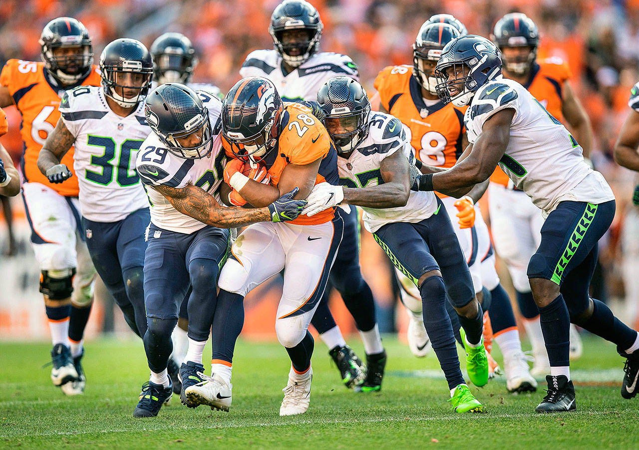On the Denver Broncos’ last drive, the Seattle Seahawks’ defense holds running back Royce Freeman five yards short of the first down marker, with Earl Thomas (29) and Tre Flowers (37) making the stop on Sunday, Sept. 9, 2018 at Mile High Stadium in Denver, Colo. Denver would not reach the first down marker, and would punt, giving the Seahawks one final chance to win the game. (Dean Rutz/Seattle Times/TNS)