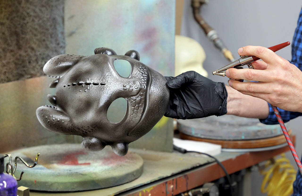 Charlie Neuman | San Diego Union Tribune                                 A mask of “Toothless,” a character from the “How to Train Your Dragon” films, is airbrushed at Disguise Inc.