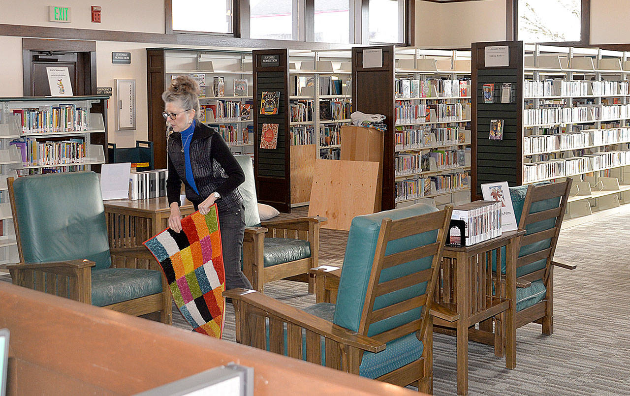 DAN HAMMOCK | GRAYS HARBOR NEWS GROUP Laurie Enholm arranges a piece of carpeting at the Hoquiam Timberland Library Friday morning.