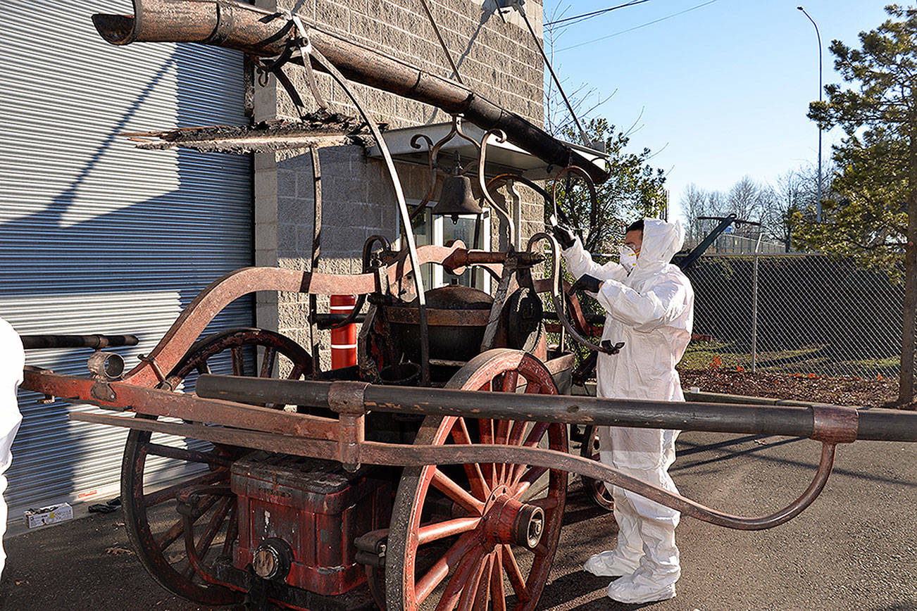 (Louis Krauss | Grays Harbor News Group)                                An employee for Restoration Management Company uses a scraper to clean the Old Tiger fire cart from the Aberdeen Museum of History.