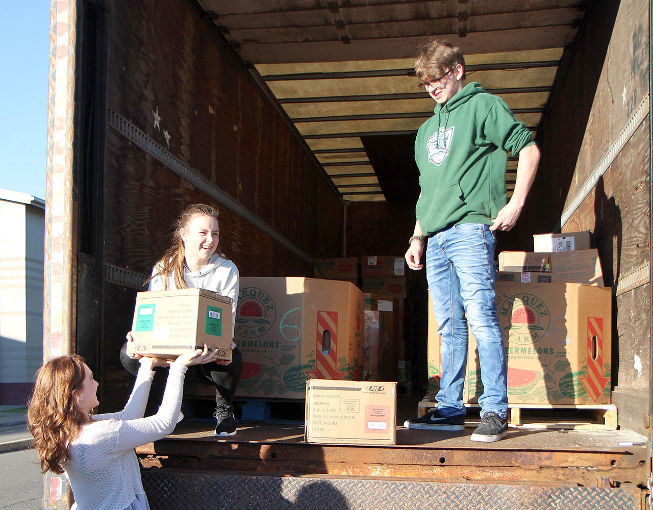 Photos by Michael Lang | Grays Harbor News Group                                Montesano High School junior Honour Iversen, from left, sophomore Cassadie Golding and senior Max Urbanski re-enact loading food for a photographer who missed the first loading Monday in Montesano.