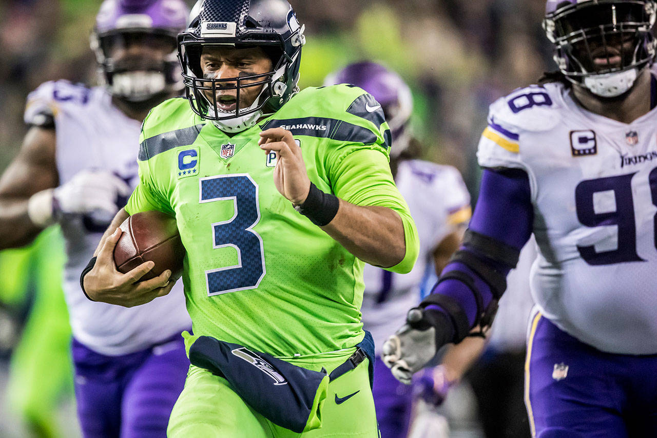 Seahawks quarterback Russell Wilson takes off on a 40-yard scramble against Vikings defensive tackle Linval Joseph, right, and defensive tackle Sheldon Richardson, left, as the Seattle Seahawks take on the Minnesota Vikings for at CenturyLink Field on Dec. 10, 2018 in Seattle. (Bettina Hansen/Seattle Times/TNS)