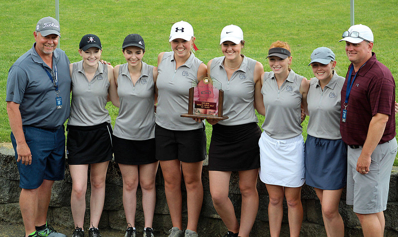 The Montesano golf team (from left) head coach Doug Galloway, Lauren Denholm, Morgan Malizia, Macey Wecker, McKenna Miller, Glory Grubb, Mylaina Parker and coach Jon Parker pose with their state championship trophy after winning the 1A/2B/1B State Tournament in May. (Photo by Angela Denholm)