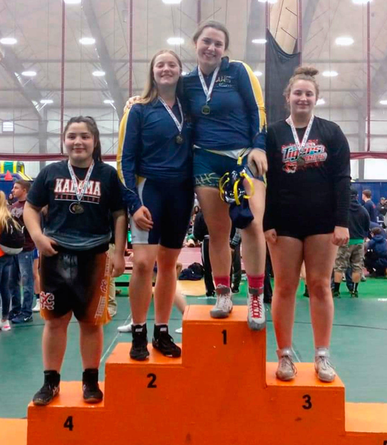 Aberdeen’s Tatum Heikkila (1) and Katie Gaskin (2) stand arm-in-arm atop the podium after finishing first and second, respectively, in the 190-pound class of the WIAA District IV North Sub-Regional Tournament at the Northwest Sports Hub in Centralia on Saturday. (Submitted photo)