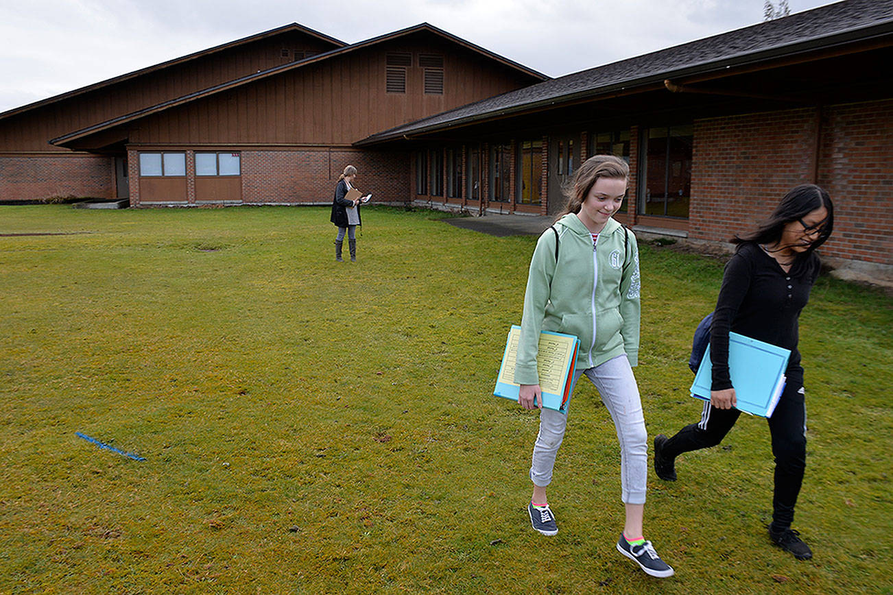 Louis Krauss | Grays Harbor News Group                                Students Jayci Johnson, left, and Aracely Padilla leave Miller Junior High last week. This grassy plot next to the school is where a modular building will go to accommodate sixth-grade-students joining the middle school next fall.