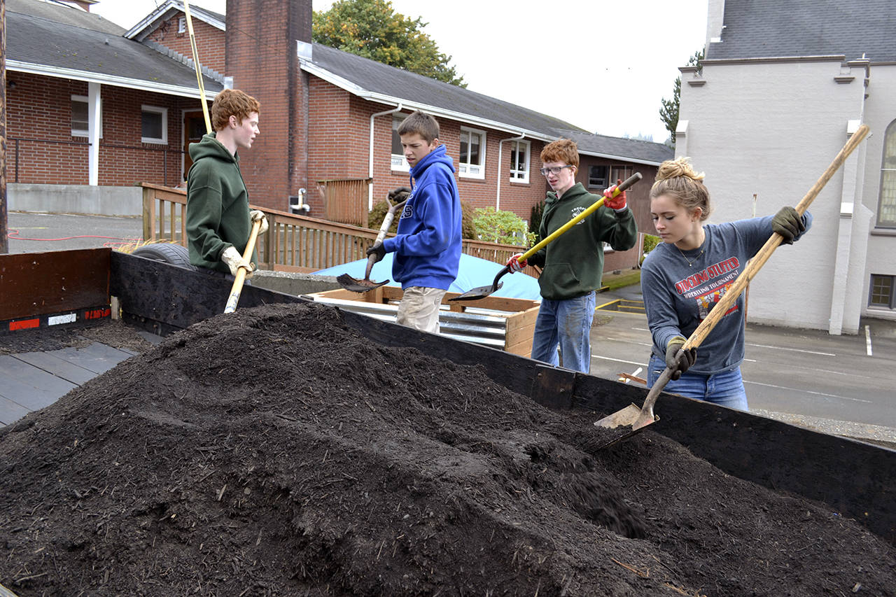 (Photo courtesy Erwin family) Trace Erwin, left, supervises volunteers (including his twin, Jared, second from right) during his project, which he calls the Landscape Reformation, at Grace Lutheran Church in Aberdeen.