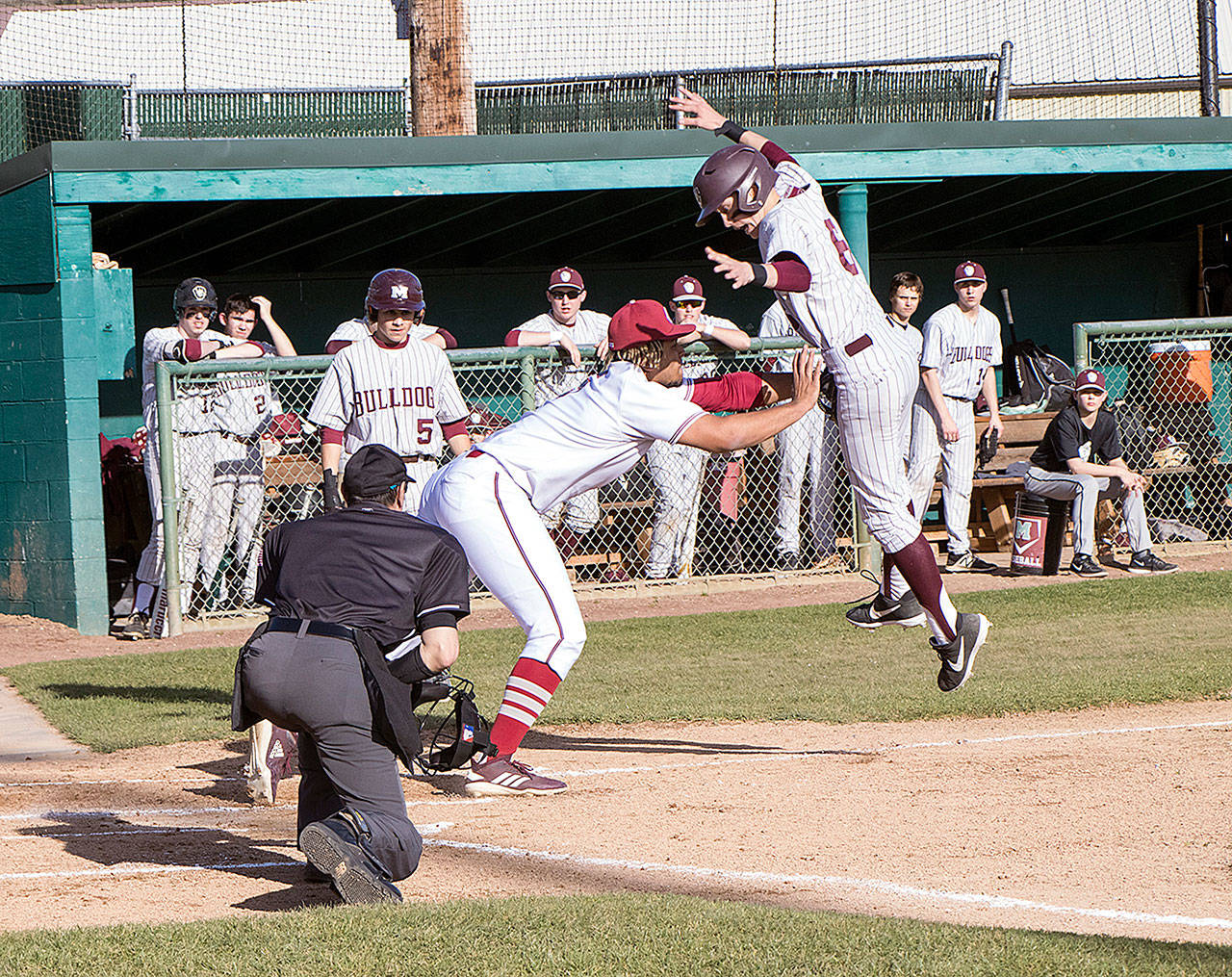 Montesano’s Cole Daniels, right, leaps to try to avoid the tag of a WF West player during the Bulldogs’ 8-3 loss on Tuesday in Chehalis. (Matt Baide | Centralia Chronicle)