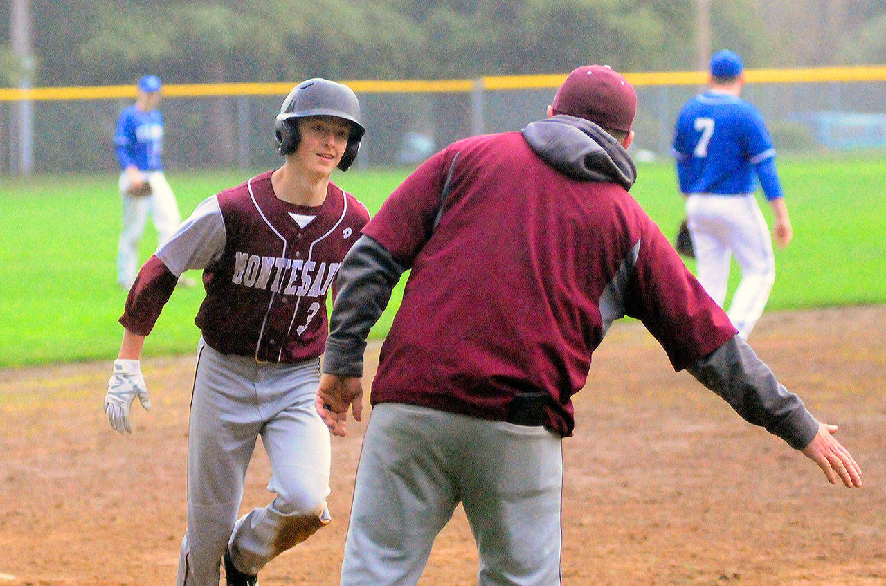 Montesano’s Braden Dohrmann is congratulated by head coach Mike Osgood as he rounds third base after hitting a home run in the fifth inning against Elma. (Hasani Grayson | Grays Harbor News Group)