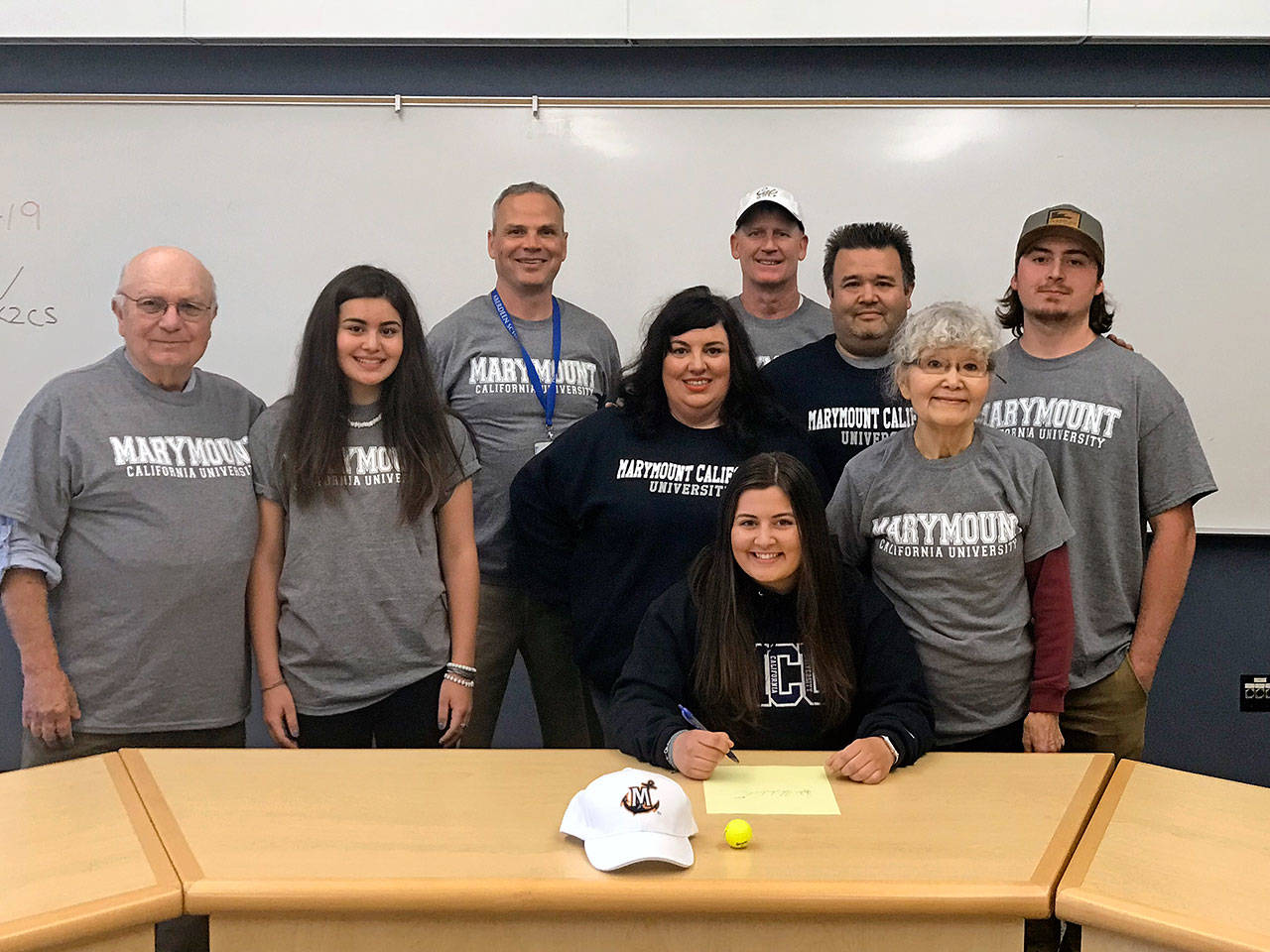 Aberdeen golfer Ryder Heikkila (sitting) is surrounded by coaches and family members as she signs a National Letter of Intent on Thursday to play for Marymount California University next season. Pictured from left: grandfather Richard Heikkila, sister Saylor Heikkila, Aberdeen Athletic Director Aaron Roiko, mother Brooke Heikkila, Aberdeen girls golf coach Dan Sundstrom, father Chris Heikkila, grandmother Yoshiko Heikkila and brother Seth Heikkila. (Submitted photo)
